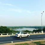 Scenic view of Bhopal city with a car driving on a road alongside the lake