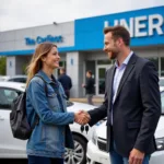 Smiling car salesman handing keys to a happy customer