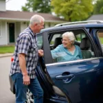 Ashford volunteer driver assisting an elderly passenger into a car